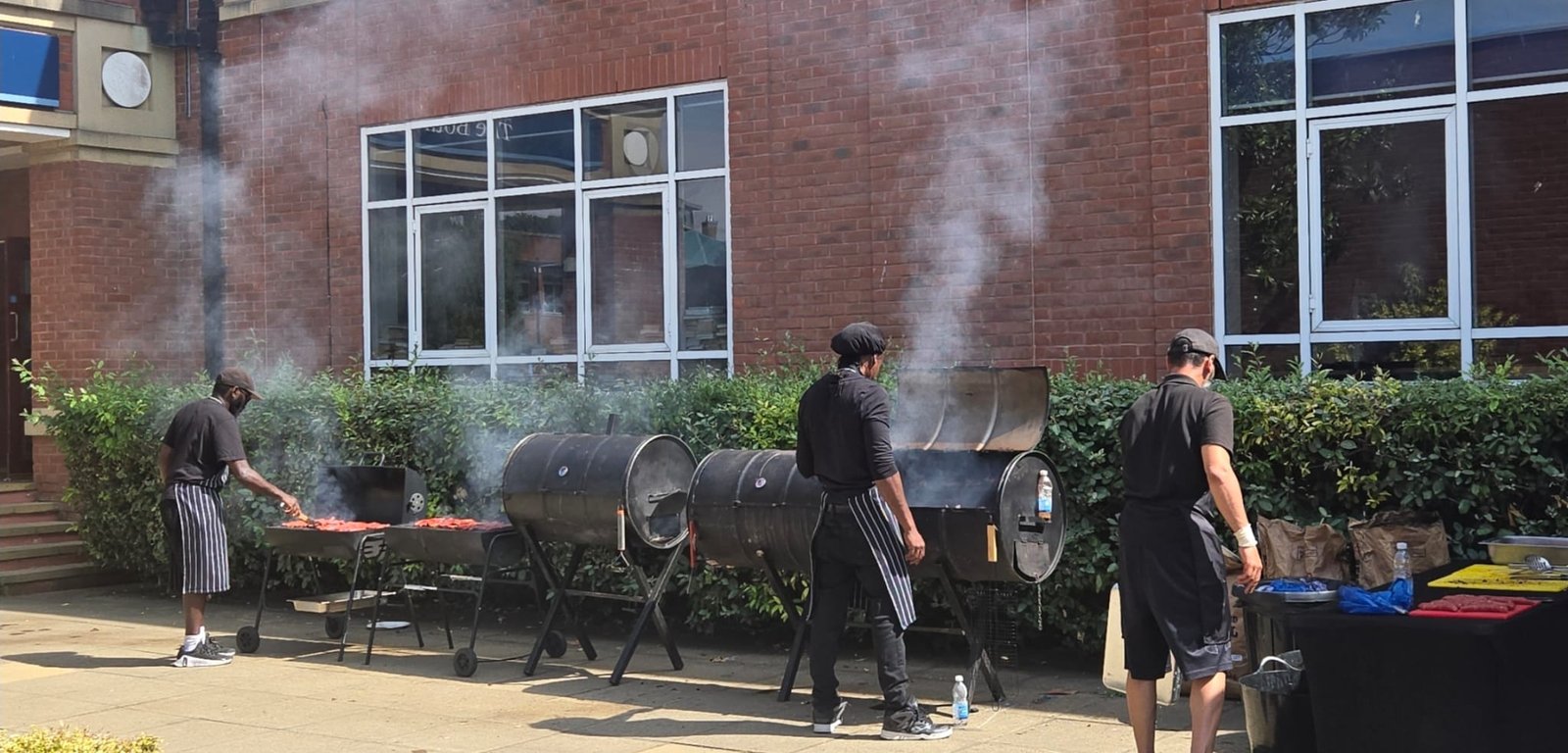 Three Grill Seekers chefs cooking beside outdoor BBQ smokers