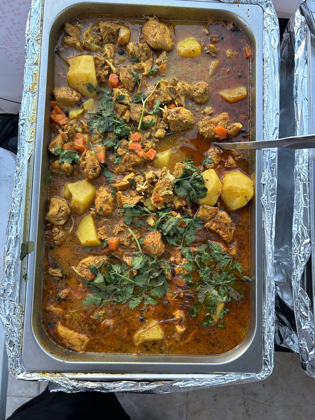 Tray of spiced chicken and potatoes garnished with fresh herbs