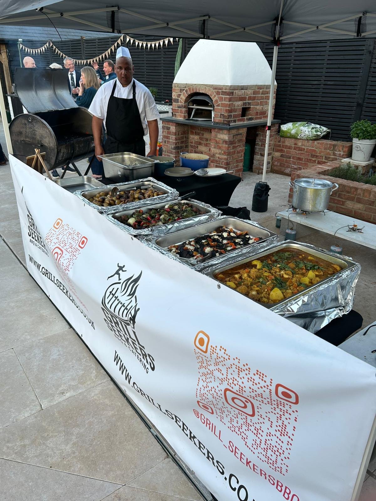 Grill Seekers chef behind an outdoor buffet of freshly prepared dishes