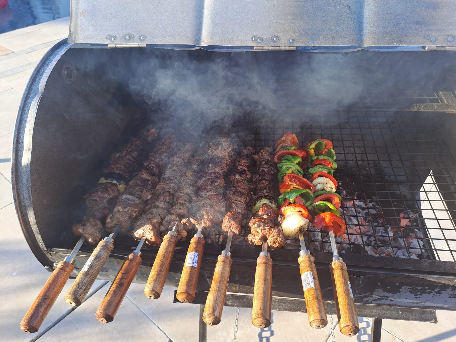 Meat and vegetable skewers cooking in a smoker